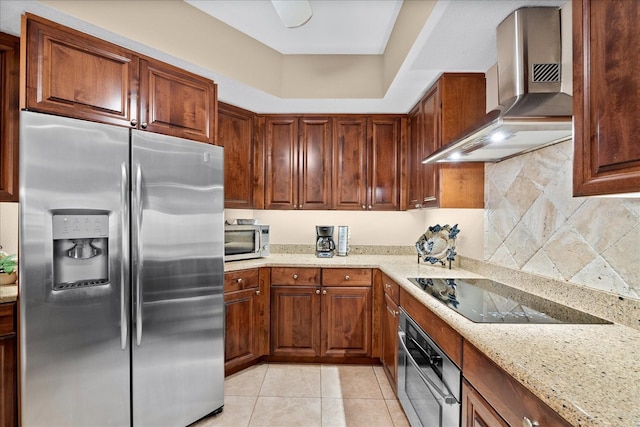 kitchen featuring light stone counters, wall chimney range hood, light tile patterned floors, and appliances with stainless steel finishes