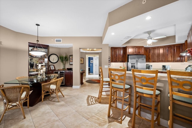 kitchen with light tile patterned floors, ceiling fan, hanging light fixtures, stainless steel refrigerator with ice dispenser, and kitchen peninsula