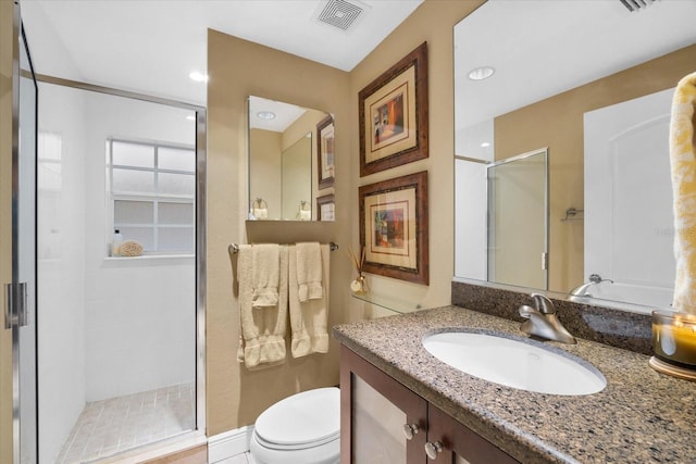 bathroom featuring tile patterned flooring, vanity, a shower with shower door, and toilet