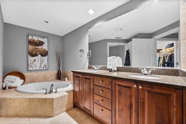 bathroom featuring a relaxing tiled tub, tile patterned floors, and vanity