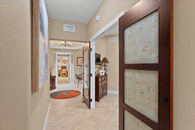 hall with a chandelier and light tile patterned floors