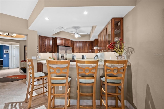 kitchen featuring appliances with stainless steel finishes, kitchen peninsula, a kitchen bar, ceiling fan, and a tray ceiling