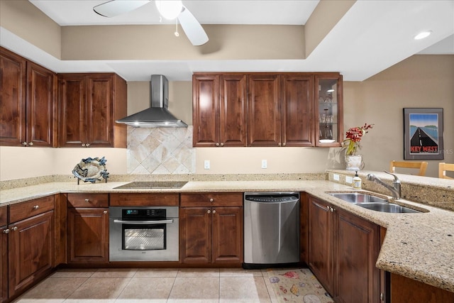 kitchen with wall chimney range hood, sink, stainless steel appliances, light stone counters, and light tile patterned flooring