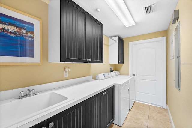 laundry area featuring cabinets, separate washer and dryer, sink, and light tile patterned floors