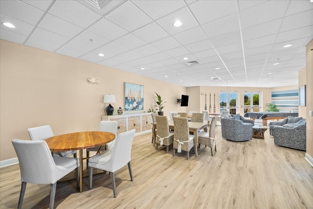 dining space with a paneled ceiling, light hardwood / wood-style floors, and french doors