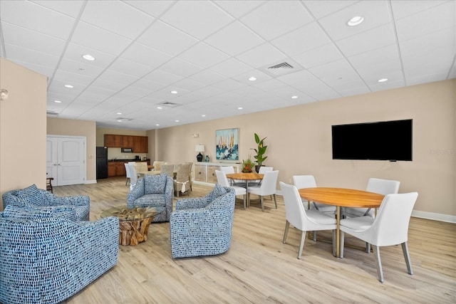 living room featuring a drop ceiling and light wood-type flooring