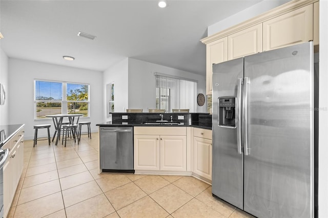 kitchen featuring light tile patterned floors, stainless steel appliances, sink, and cream cabinetry