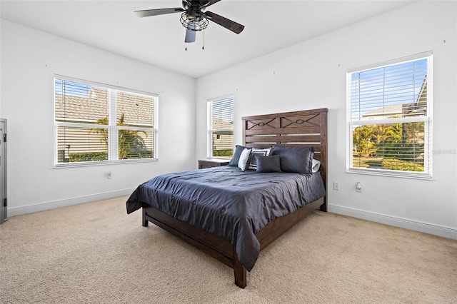 bedroom featuring ceiling fan, light colored carpet, and multiple windows