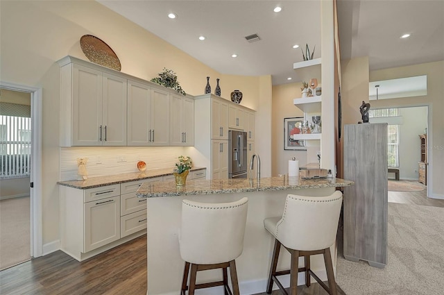 kitchen with white cabinetry, a wealth of natural light, stainless steel fridge, and light stone counters