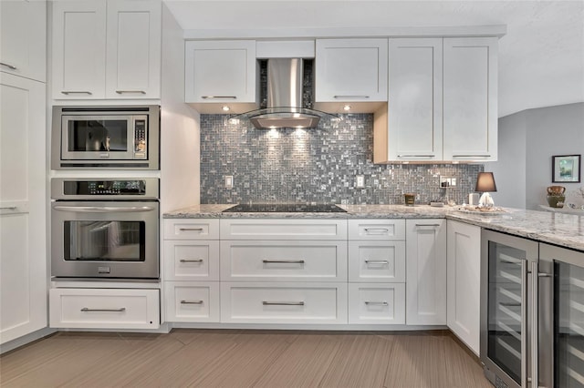 kitchen featuring appliances with stainless steel finishes, light stone counters, wall chimney exhaust hood, white cabinets, and tasteful backsplash