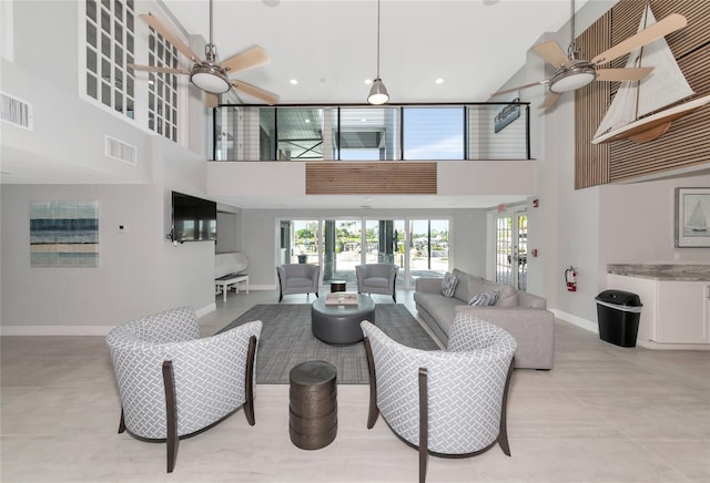 living room featuring ceiling fan, light tile patterned floors, and a high ceiling