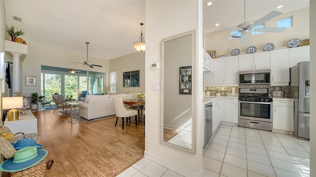 kitchen with tasteful backsplash, appliances with stainless steel finishes, white cabinets, and high vaulted ceiling