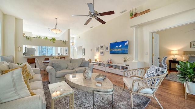 living room with hardwood / wood-style floors, a high ceiling, ceiling fan, and ornate columns