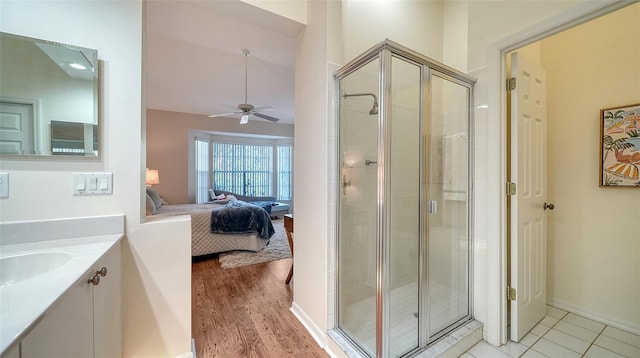 bathroom with a shower with shower door, lofted ceiling, hardwood / wood-style flooring, vanity, and ceiling fan