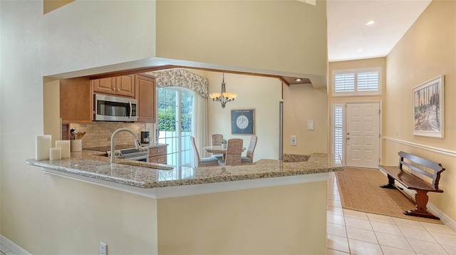 kitchen featuring light stone countertops, sink, and kitchen peninsula