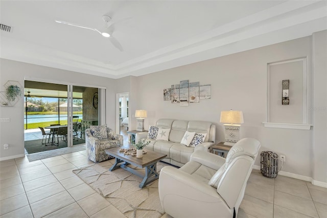 living room with light tile patterned floors, a tray ceiling, and ceiling fan