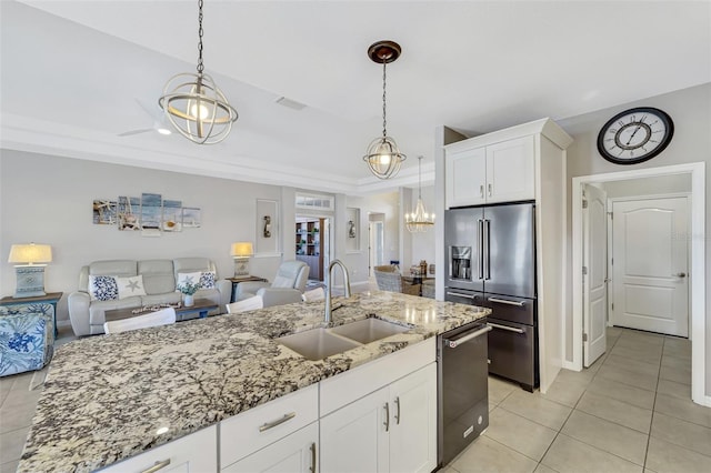 kitchen with sink, appliances with stainless steel finishes, light stone countertops, white cabinets, and decorative light fixtures