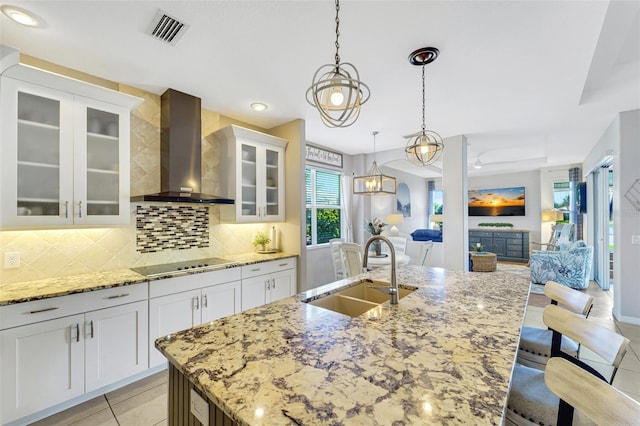 kitchen with white cabinetry, sink, a kitchen bar, black electric stovetop, and wall chimney exhaust hood