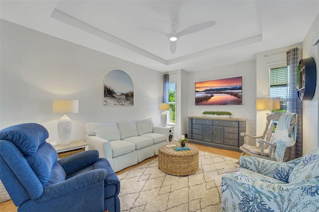 living room with ceiling fan, a tray ceiling, and a wealth of natural light