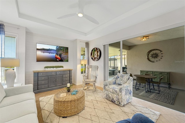 living room featuring ceiling fan and a tray ceiling