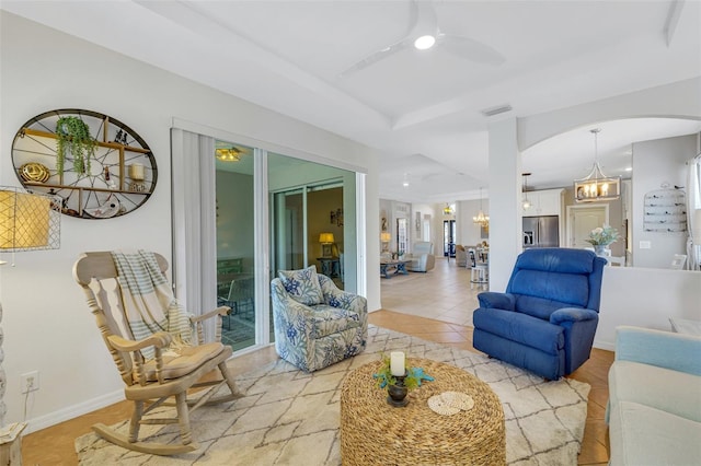 living room featuring light tile patterned floors and ceiling fan with notable chandelier