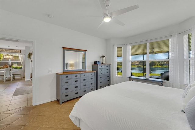 tiled bedroom featuring ceiling fan and a water view