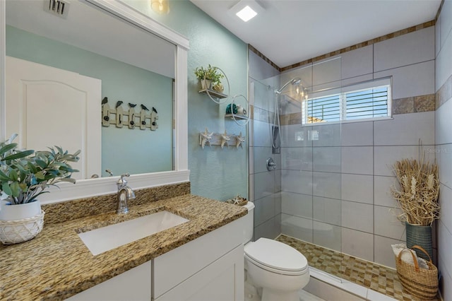 bathroom with vanity, toilet, and tiled shower