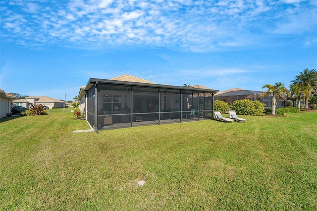 rear view of house featuring a lawn and a sunroom