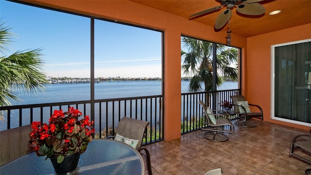 sunroom / solarium with a water view and ceiling fan