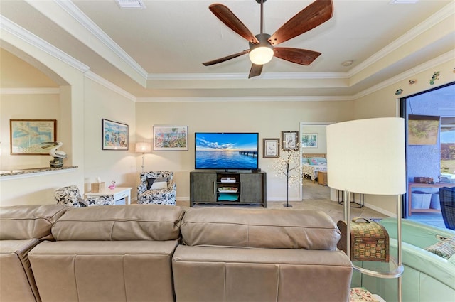 living room featuring ceiling fan, ornamental molding, a tray ceiling, and carpet