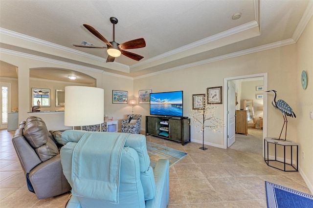 tiled living room with crown molding, a tray ceiling, and ceiling fan