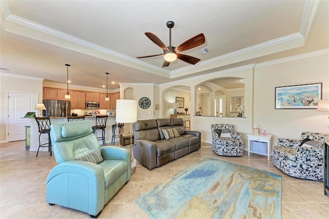 living room with crown molding, ceiling fan, a raised ceiling, and light tile patterned flooring