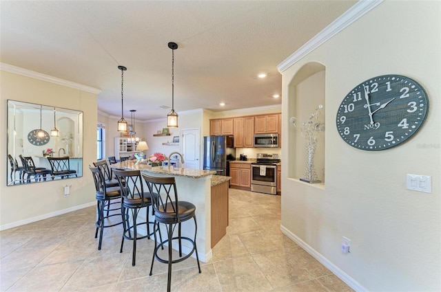 kitchen with a kitchen bar, light stone counters, hanging light fixtures, ornamental molding, and appliances with stainless steel finishes