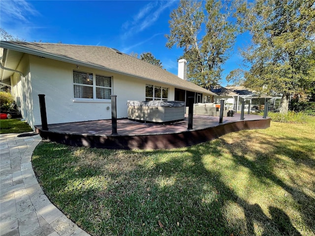 rear view of house featuring a wooden deck, a yard, and a hot tub