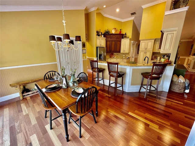 dining room with sink, crown molding, high vaulted ceiling, a notable chandelier, and light wood-type flooring