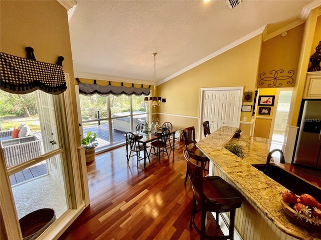 dining area featuring crown molding, an inviting chandelier, vaulted ceiling, a textured ceiling, and dark hardwood / wood-style floors