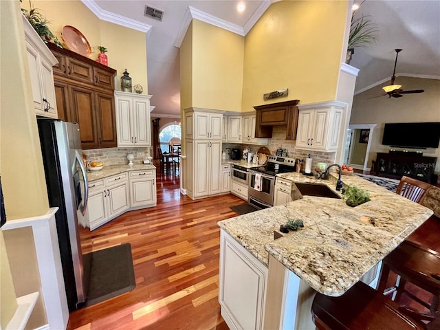 kitchen with a breakfast bar, sink, tasteful backsplash, appliances with stainless steel finishes, and kitchen peninsula