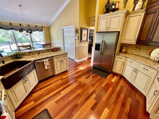 kitchen featuring ornamental molding, stainless steel appliances, vaulted ceiling, and cream cabinetry