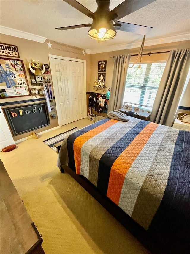 bedroom featuring a textured ceiling, ornamental molding, a closet, ceiling fan, and carpet