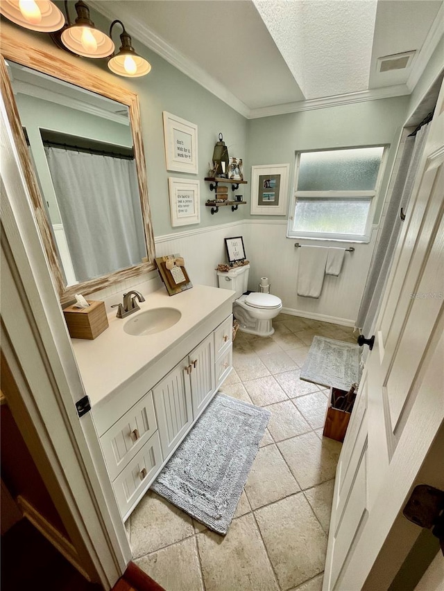 bathroom with tile patterned floors, ornamental molding, toilet, and vanity