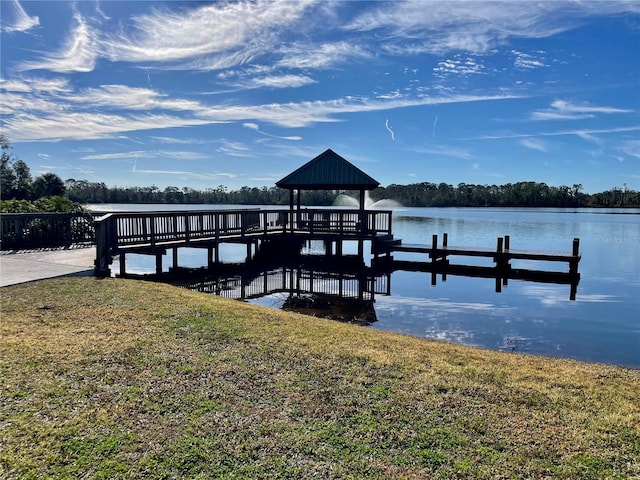view of dock with a gazebo, a water view, and a lawn