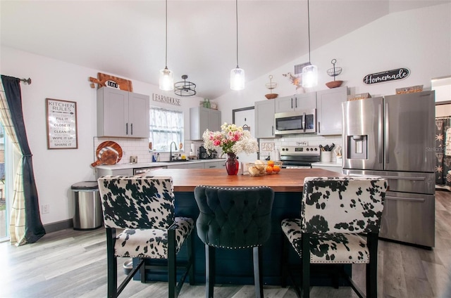 kitchen with tasteful backsplash, lofted ceiling, appliances with stainless steel finishes, and butcher block counters