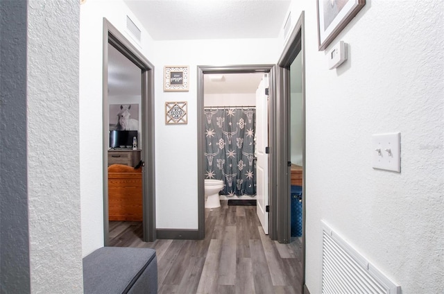 hallway with hardwood / wood-style flooring and a textured ceiling