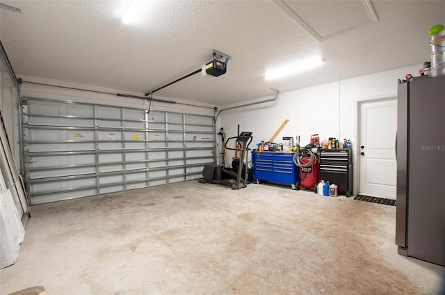 garage featuring a garage door opener and stainless steel refrigerator