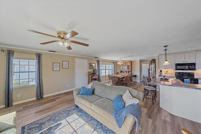 living room with crown molding, ceiling fan, and light hardwood / wood-style floors