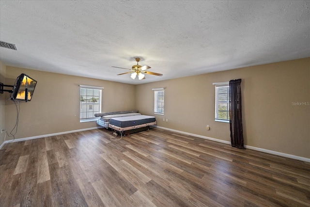 unfurnished bedroom with ceiling fan, a textured ceiling, and dark hardwood / wood-style flooring