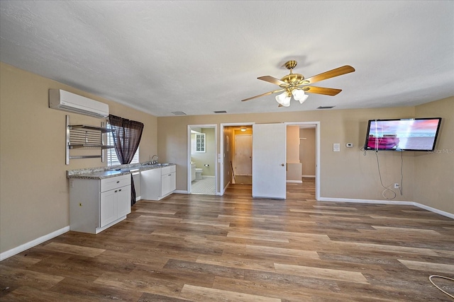 kitchen featuring hardwood / wood-style flooring, sink, a wall unit AC, and white cabinets