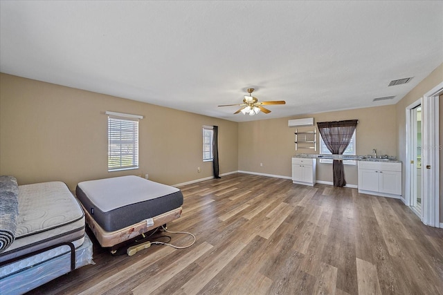 interior space featuring ceiling fan, a wall mounted air conditioner, sink, and light hardwood / wood-style floors