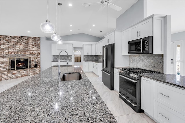 kitchen with lofted ceiling, sink, high end black refrigerator, gas range oven, and white cabinets