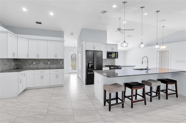 kitchen with sink, dark stone countertops, black appliances, an island with sink, and white cabinets